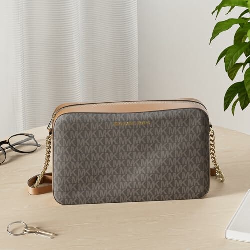 Brown designer handbag with MK pattern on a table.