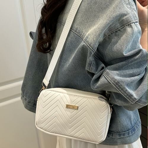 Person wearing a denim jacket with a white crossbody bag.