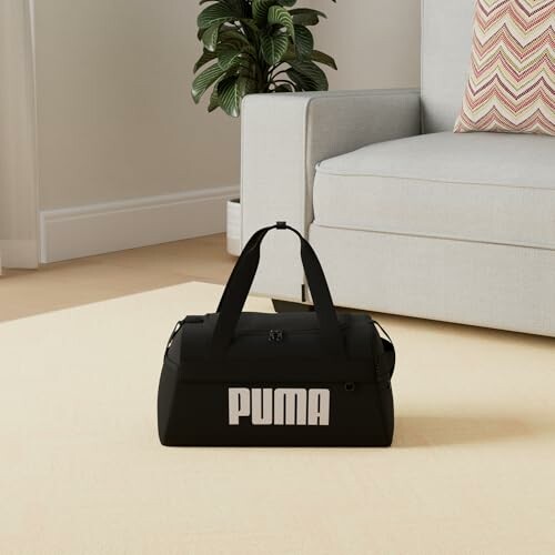 Black gym duffel bag on living room floor near a sofa.
