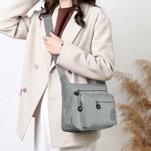 Woman wearing a beige coat and holding a gray crossbody bag.