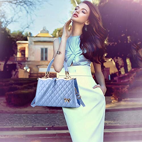 Woman in elegant attire holding a blue quilted handbag outdoors.